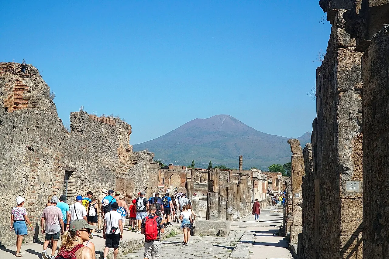 Besucher auf der Straße zum Forum von Pompeji, mit dem Vesuv in der Ferne