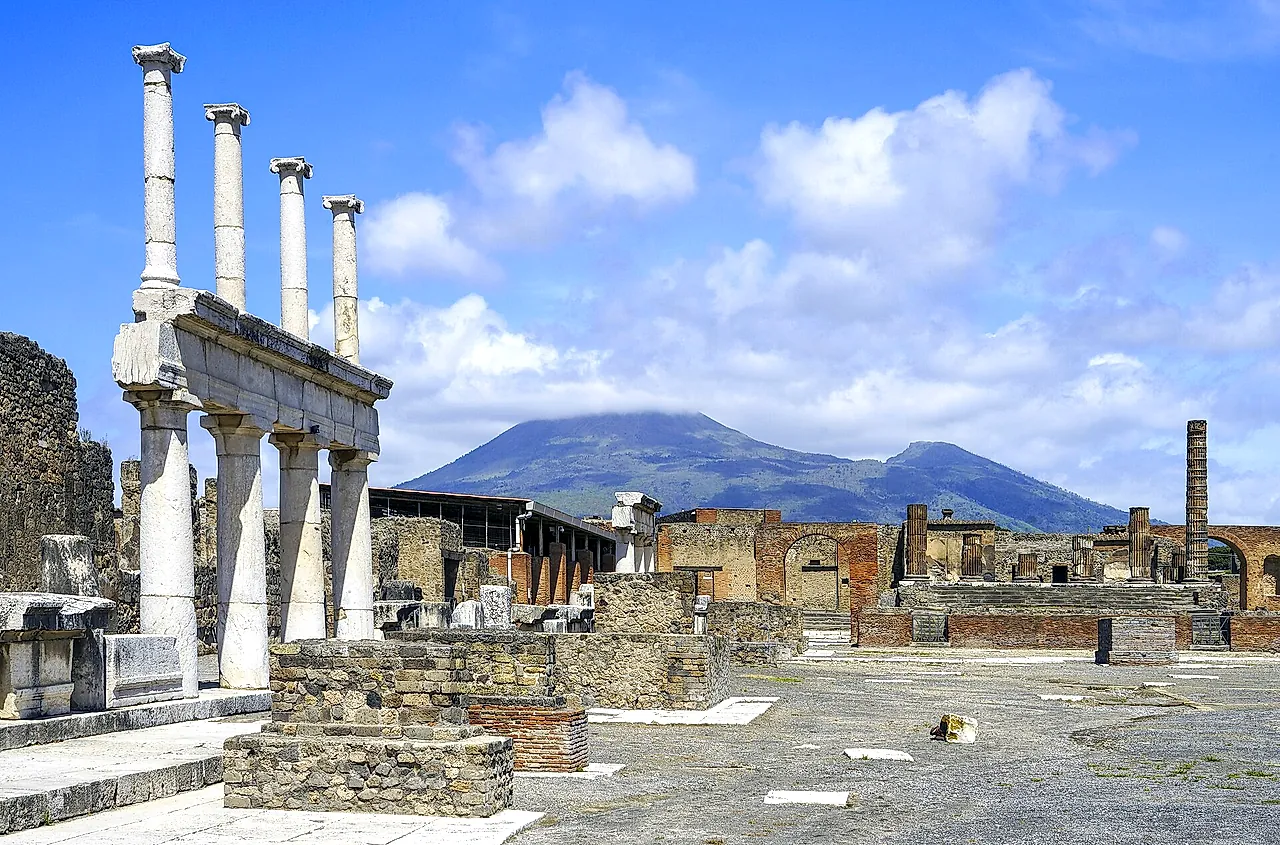 El Foro de Pompeya con la columnata blanca en primer plano y el Vesubio elevándose tras las ruinas