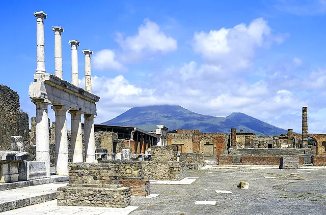 El Foro de Pompeya con la columnata blanca en primer plano y el Vesubio elevándose tras las ruinas