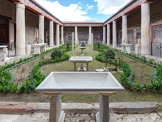 El jardín del peristilo de la Casa de los Vettii de Pompeya, con pilas de mármol y una columnata