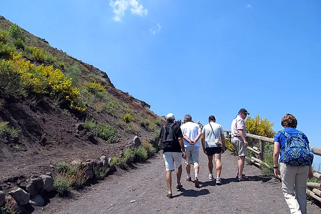 Excursionistas subiendo por el sendero de grava hacia el cráter de la cima del Vesubio